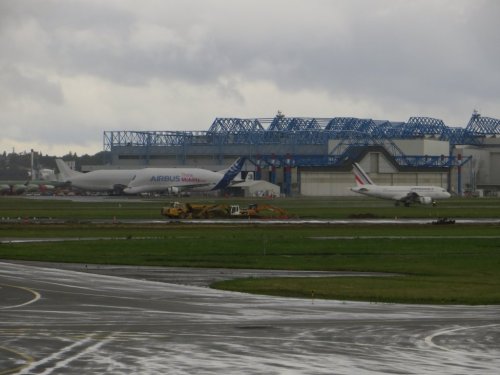 Blick auf die andere Seite: Startender AF A319(?), zwei A300-600ST und diverse Rumpfteile vor den Montagehallen.